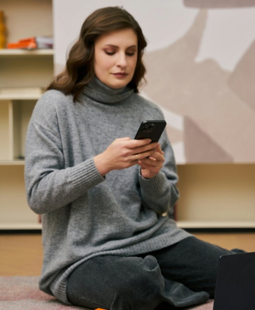 a woman sitting on the floor looking at her cell phone